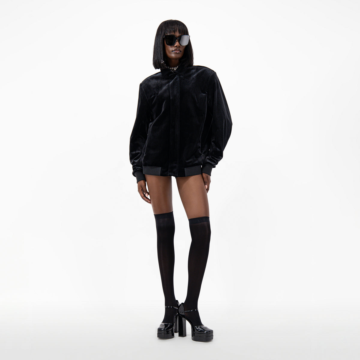 Model wearing a Black Velvet Bomber Jacket, styled with knee-high socks and platform shoes.