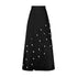 Cowrie detail denim maxi skirt in black with circular cut-outs and embellishments, featuring a high-waisted A-line design.