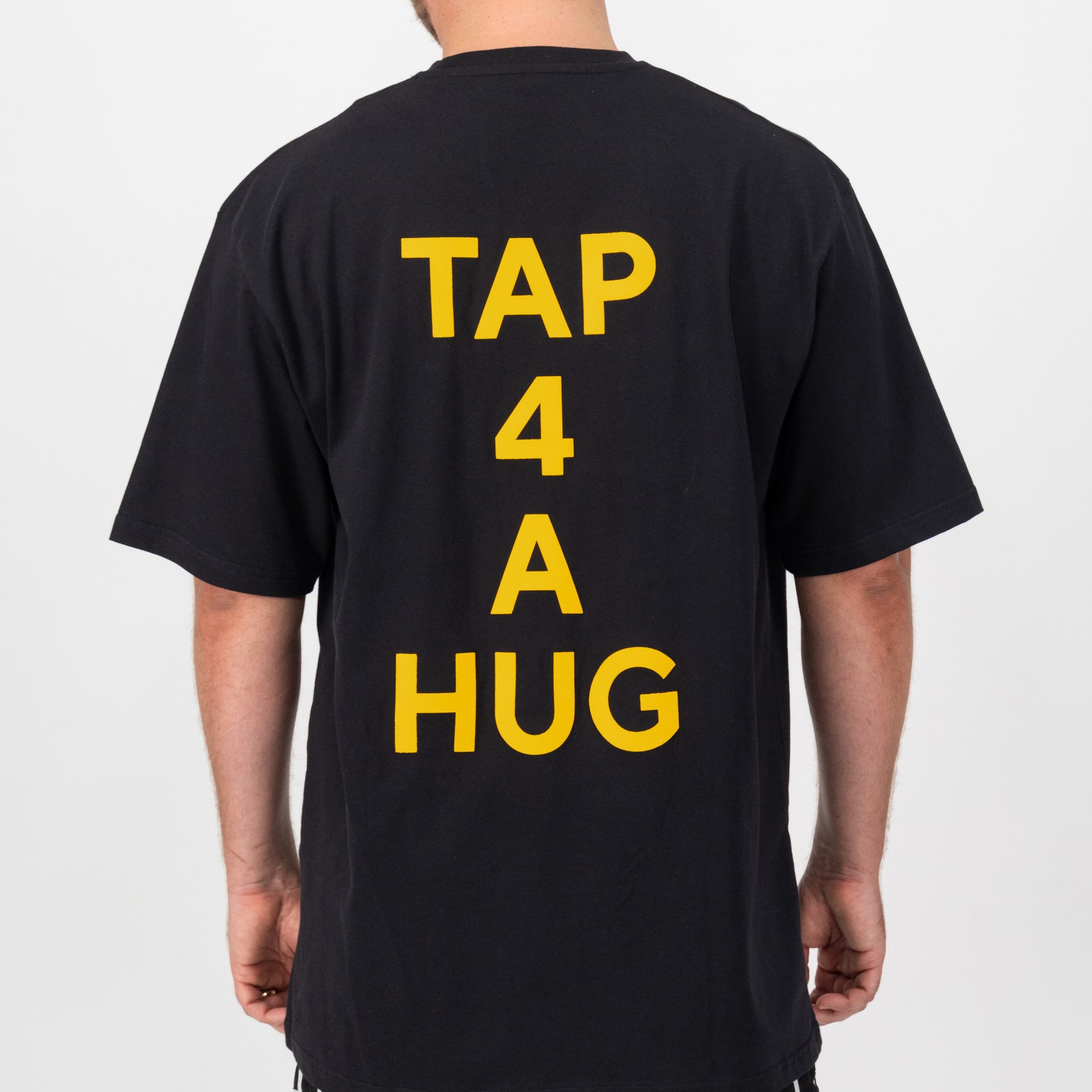 Oversized black T4AH Tee with 'TAP 4 A HUG' print detail on the back, showcasing a gender-neutral design.