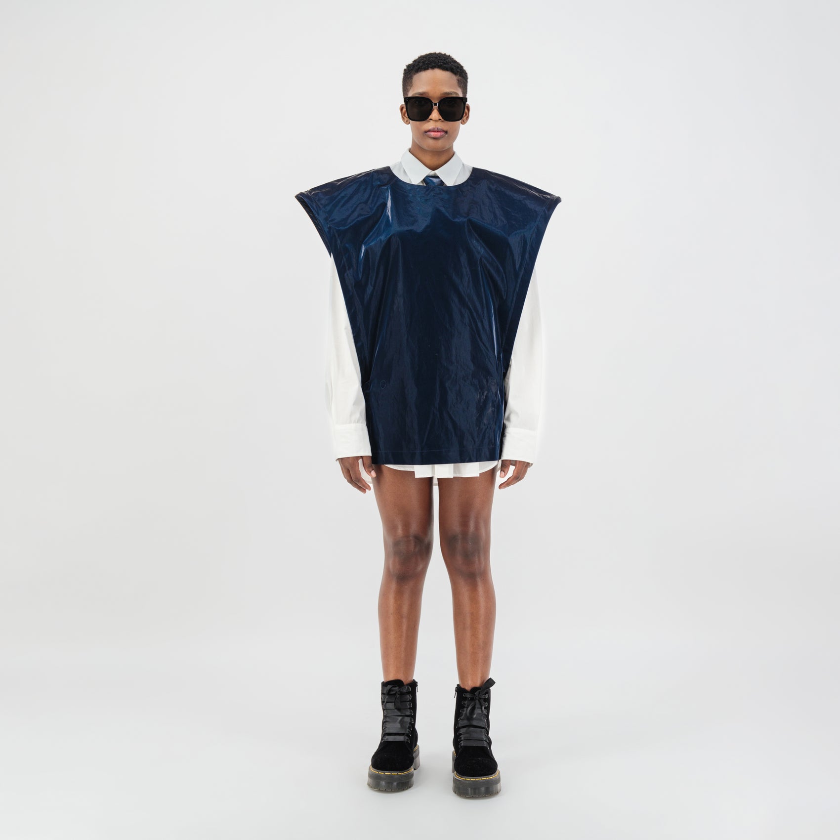 Model wearing a women's oversized metal vest in navy blue, showcasing avant-garde style and structured silhouette.